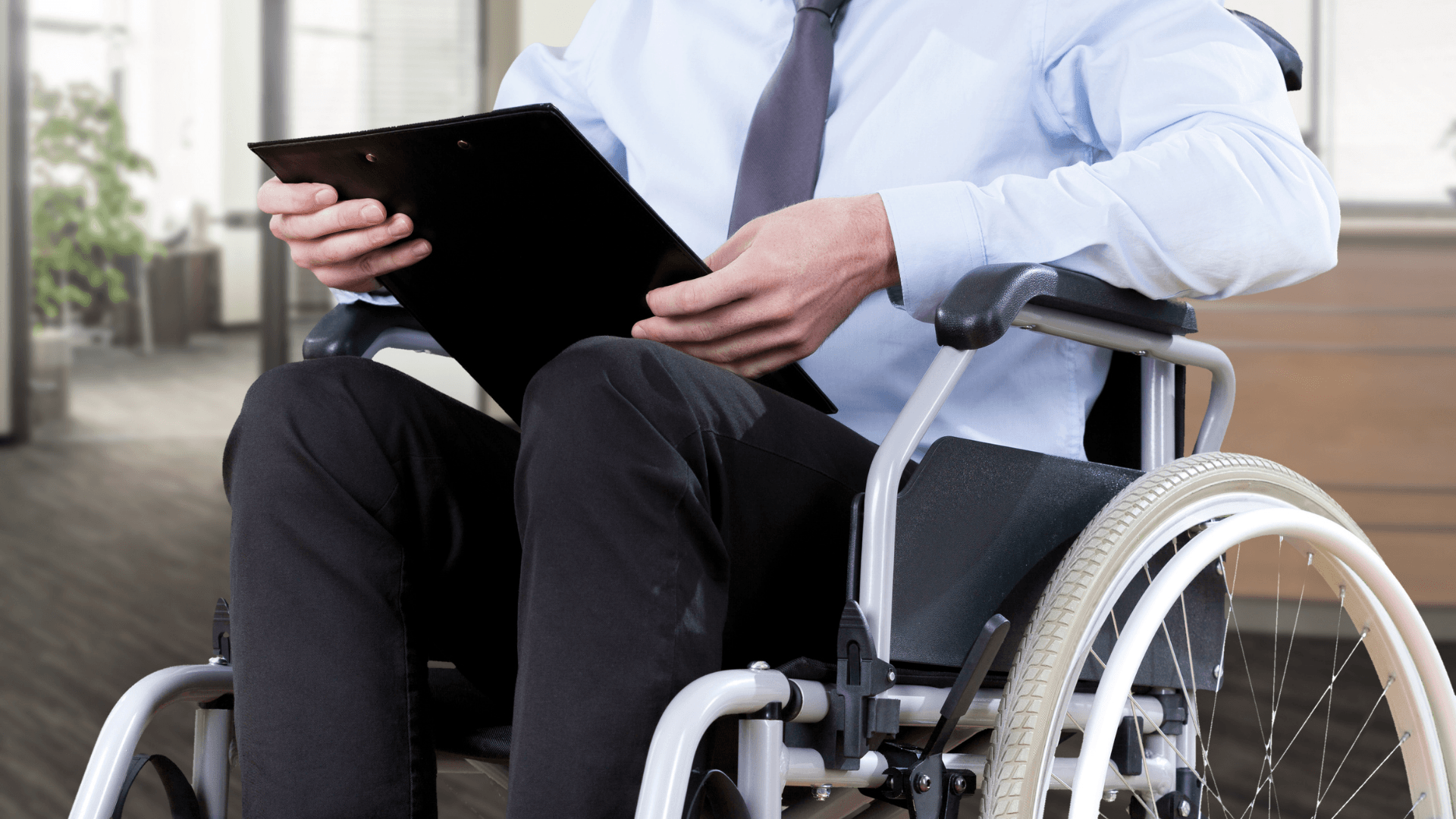 A man sits in a wheelchair holding a clipboard. The more than capable abilities of people with disabilities makes many people wonder why some people are reluctant to hire a person with a disability.